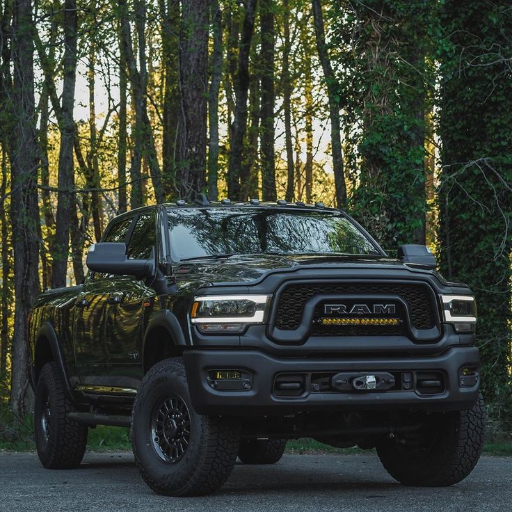 a black ram truck parked in front of some trees