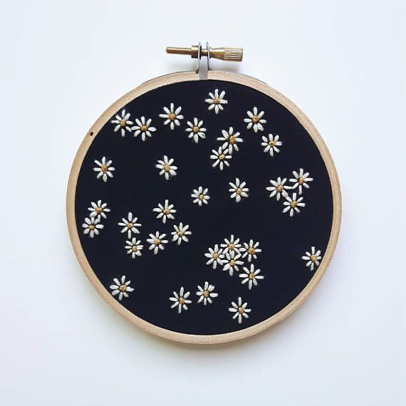 a black and white flower embroidered on a wooden hoop