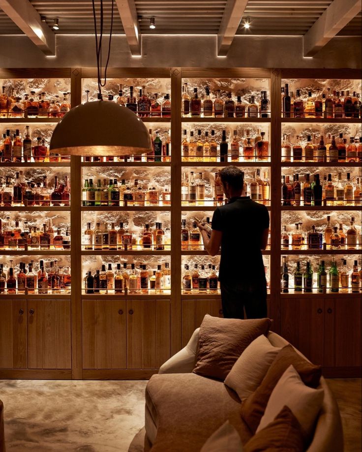 a man standing in front of a wall full of liquor bottles