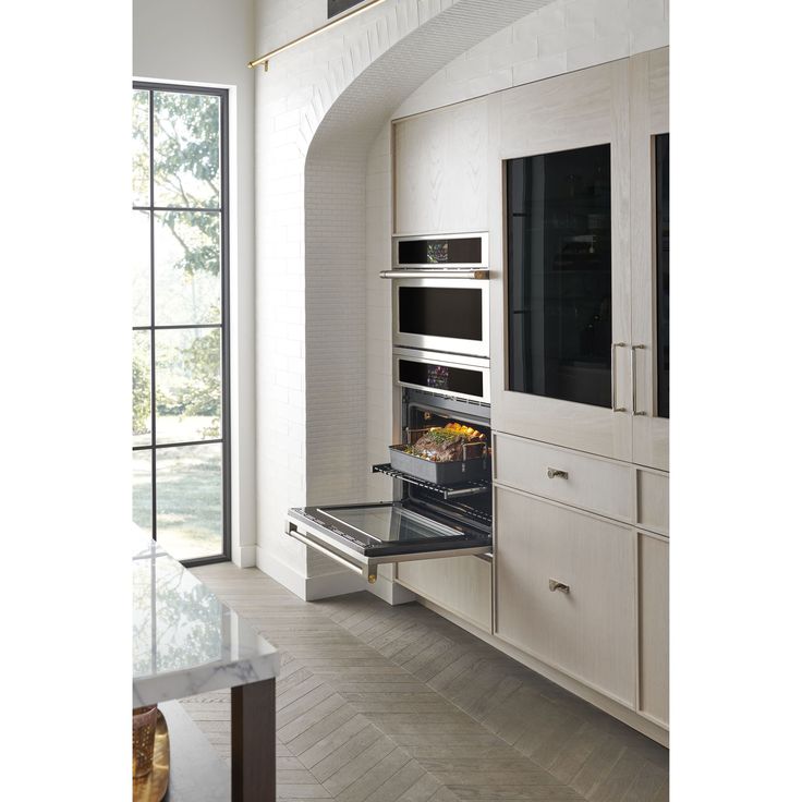 an oven with the door open in a large kitchen next to a wall mounted microwave