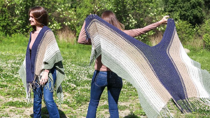 two women are walking in the grass with their shawl