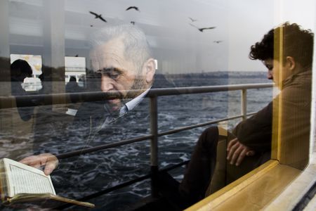 a man sitting on a boat looking out the window at seagulls flying over him