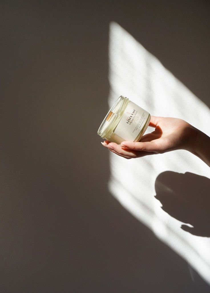 a person holding a jar of cream in their hand