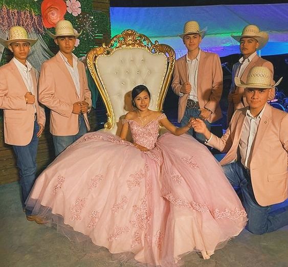 a group of people dressed in pink posing for a photo with a woman sitting on a chair