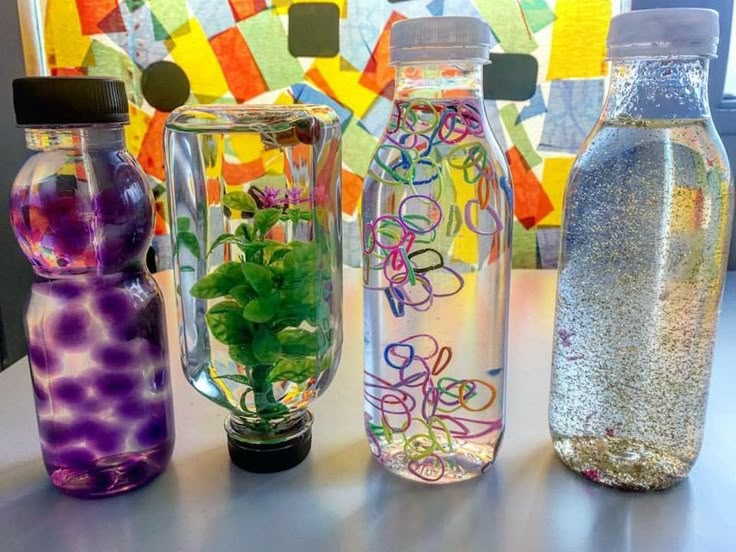 four water bottles with plants in them sitting on a table