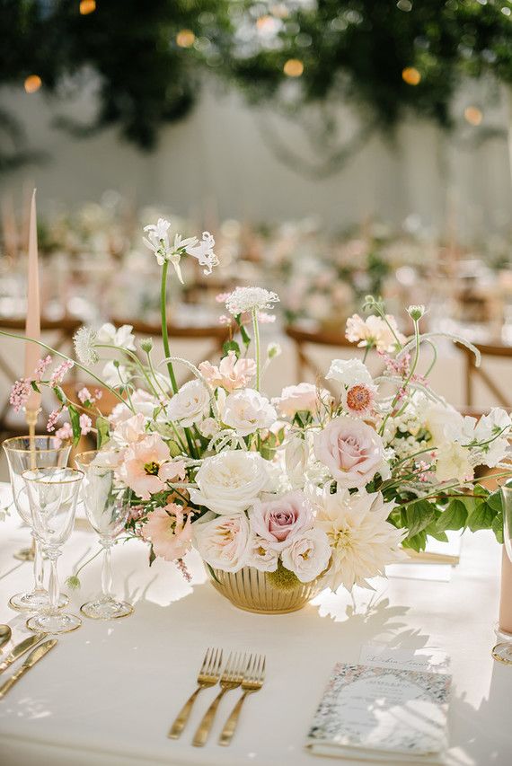 the centerpieces on this table are filled with pink and white flowers