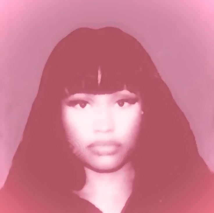 a woman with long black hair wearing a hoodie and looking at the camera while standing in front of a pink background