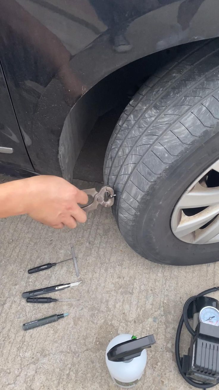 someone is changing the tire on their car with wrenches and other items around it