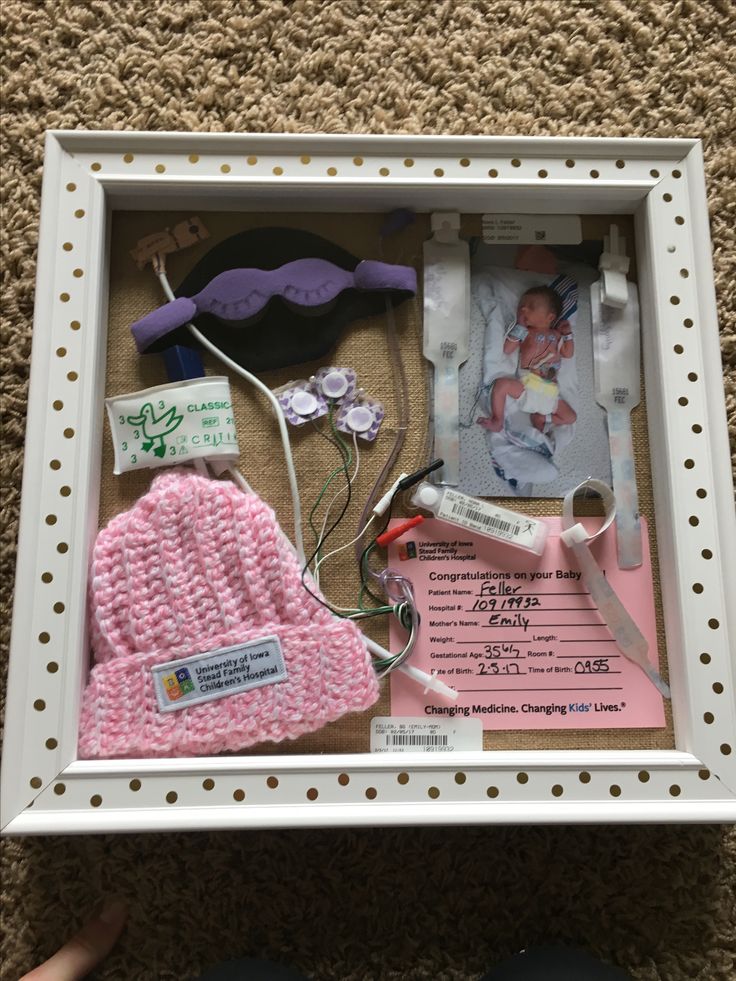 a baby's photo in a white frame with pink and purple knitted items