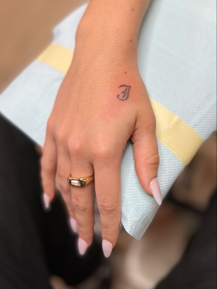 a woman's hand with a small tattoo on her left thumb and the letter f