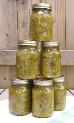 six jars filled with pickles sitting on top of a table