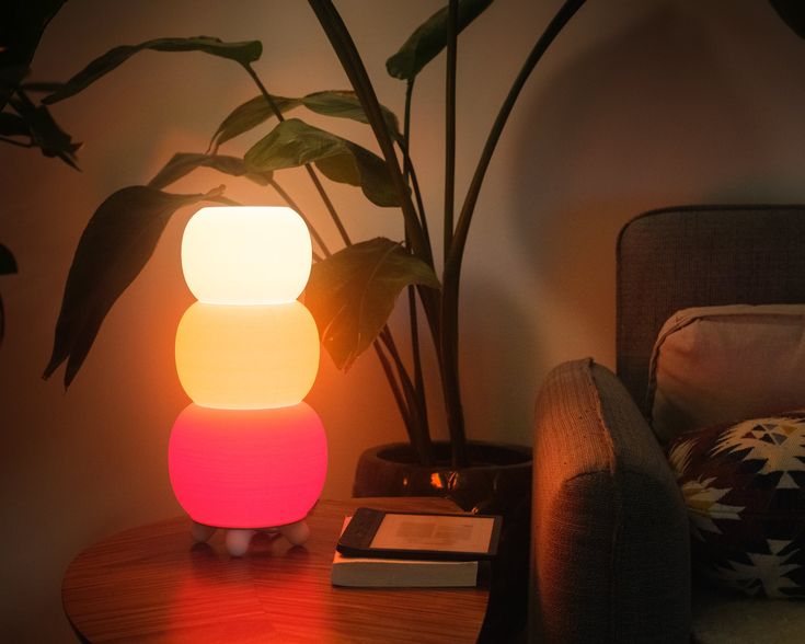 a table with a lamp on it next to a couch and a potted plant