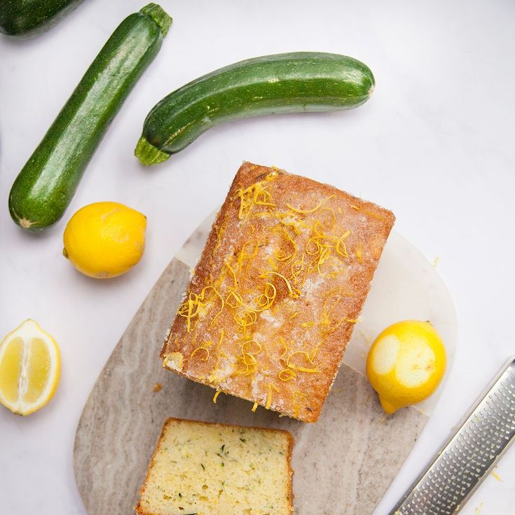 slices of lemon zucchini bread on a cutting board next to cucumbers