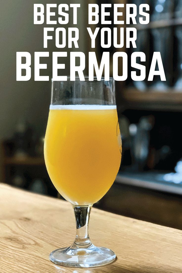 a glass filled with beer sitting on top of a wooden table