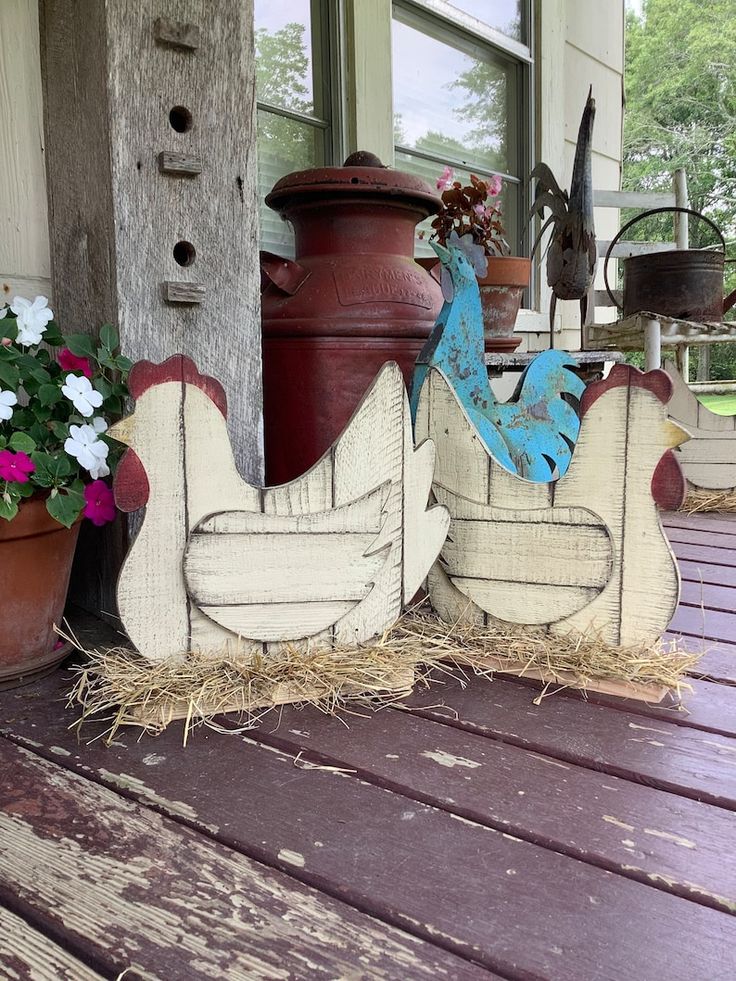 two chicken sculptures sitting on top of a wooden porch