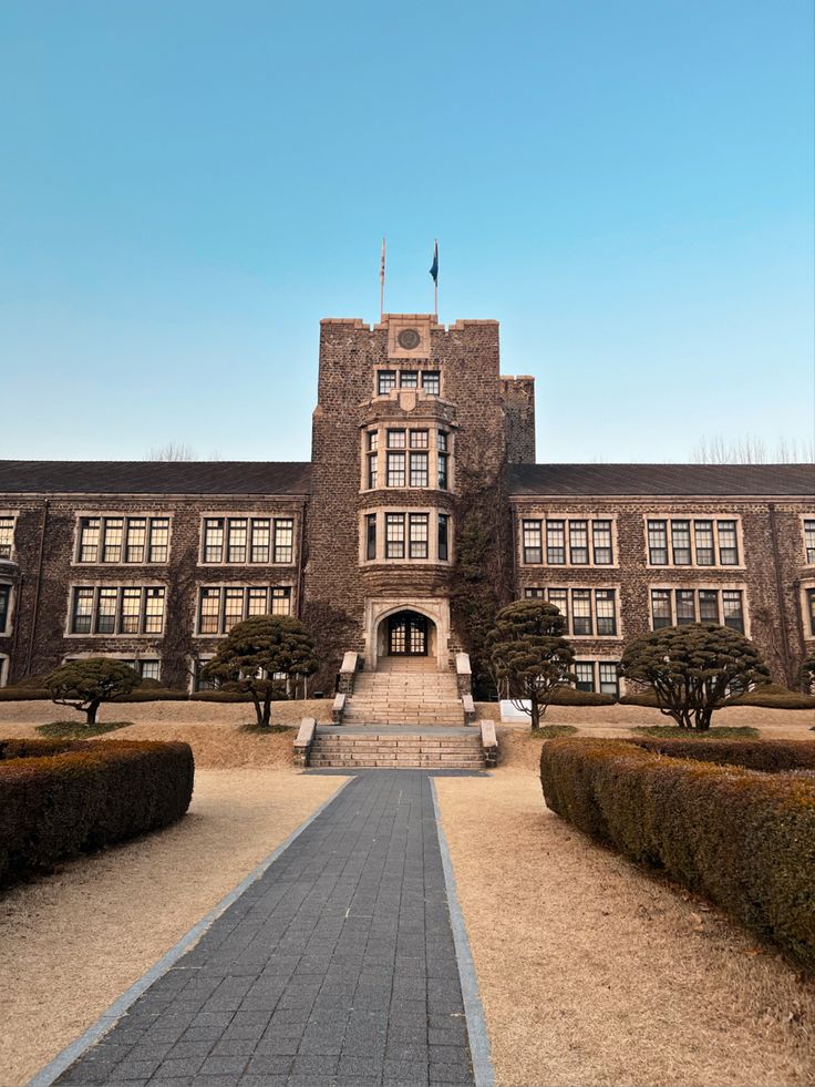 a large building with many windows and bushes around it's entrance walkway leading up to the front door