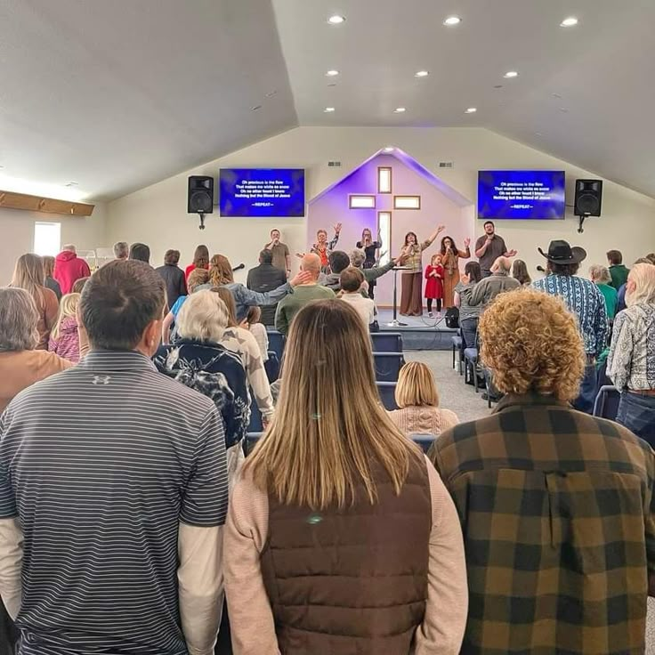 a large group of people standing in front of a church with blue screens on the wall