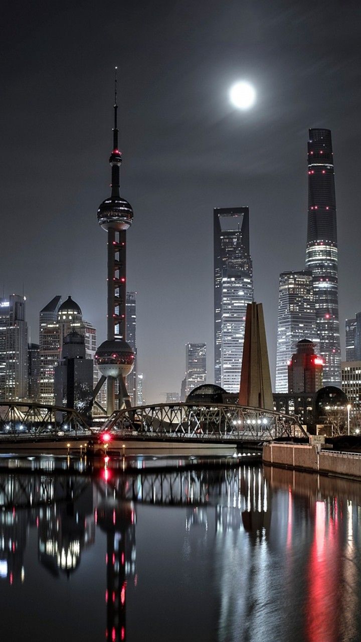 the city skyline is lit up at night with lights reflecting in the water and skyscrapers