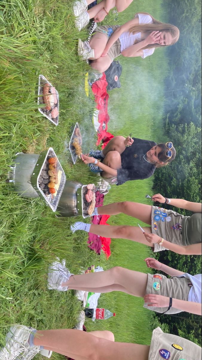 a group of people standing around each other in the grass with food on trays