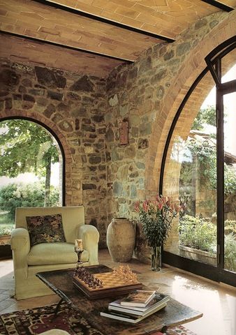 a living room filled with furniture next to an arched glass door and window overlooking a lush green field