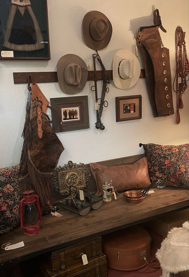 hats and other items are hanging on the wall above a bench in a room filled with old suitcases