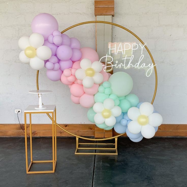 a birthday balloon arch with pastel balloons