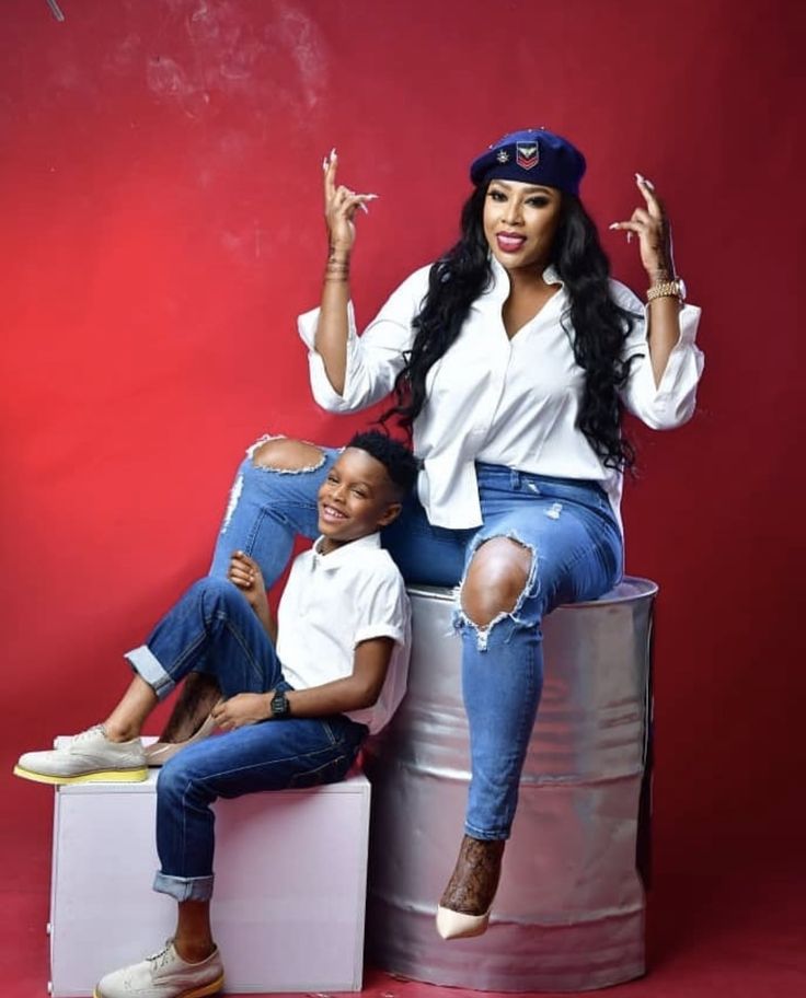 a woman sitting on top of a metal barrel next to a little boy in jeans