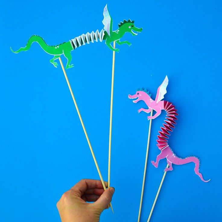 someone is holding up some cupcake toppers with dinosaurs on them and one has a toothpick in the shape of a dragon