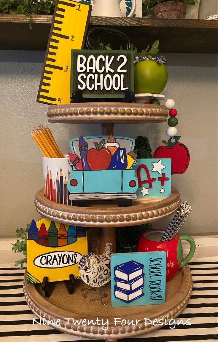 a three tiered tray with school supplies on it and the words back to school