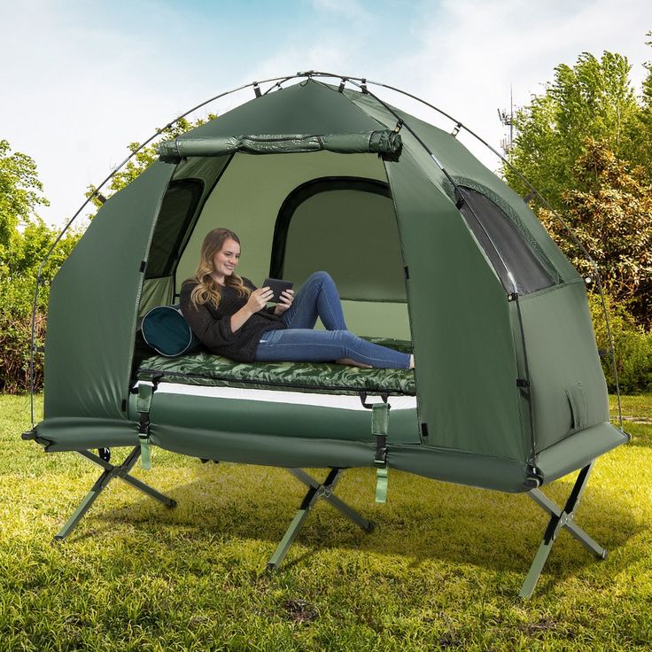 a woman laying on top of a green tent