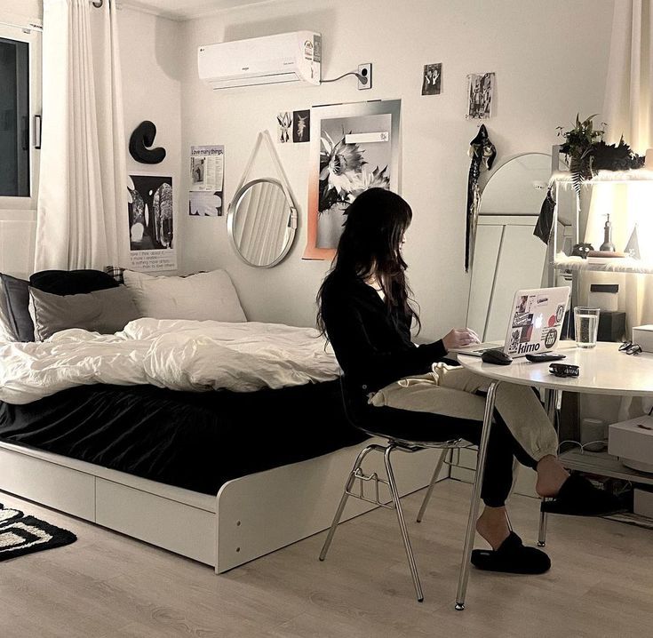 a woman sitting at a desk in front of a bed