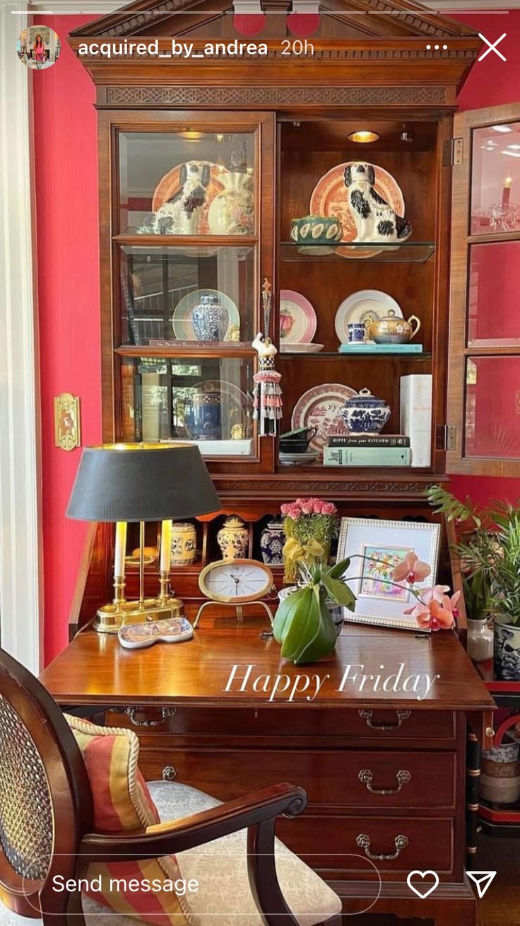 a wooden desk topped with a lamp next to a china cabinet