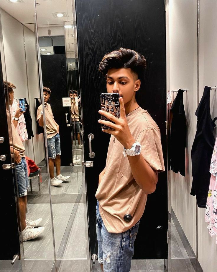 a young man taking a selfie in front of a mirror with his cell phone