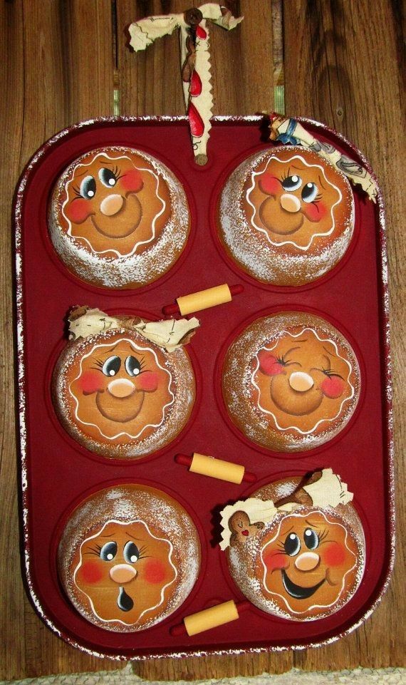 four cupcakes with faces on them in a muffin pan