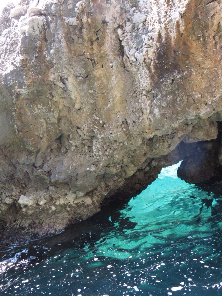 the water is crystal blue and clear in this cave entrance, which looks like it's coming out of an ocean