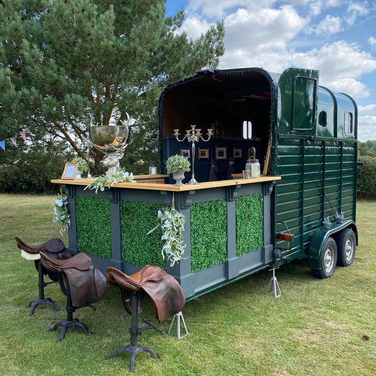 a horse trailer is decorated with artificial grass and plants for an outdoor bar or event