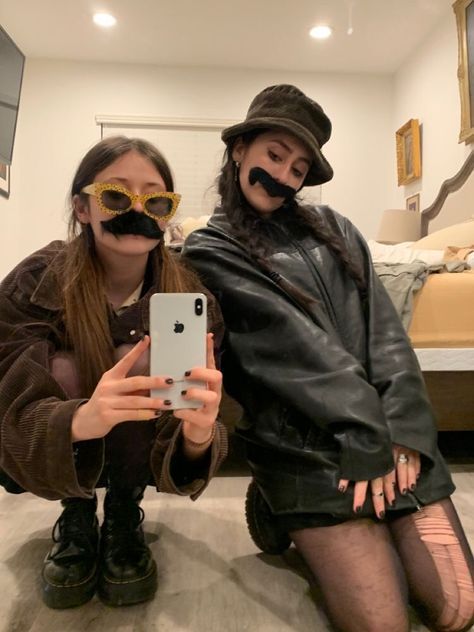 two people with fake moustaches are taking a selfie