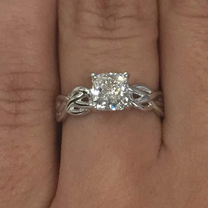 a woman's hand with a diamond ring on top of her finger and the other hand holding an engagement ring