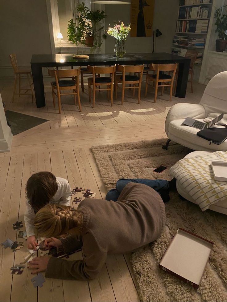 a young child playing with puzzle pieces on the floor in a living room next to a couch