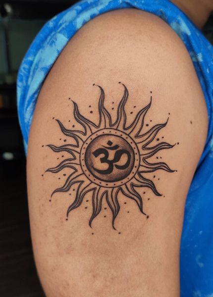 a sun tattoo with an om symbol on the upper half of it's arm