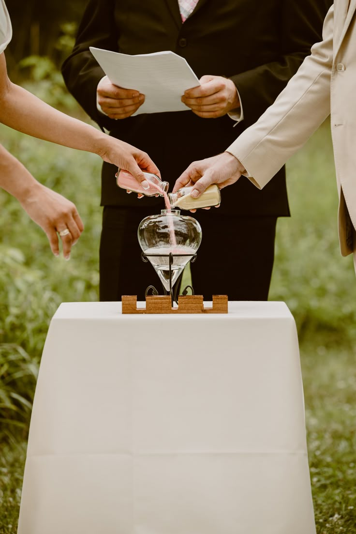 two people standing at a table with an hourglass in front of them