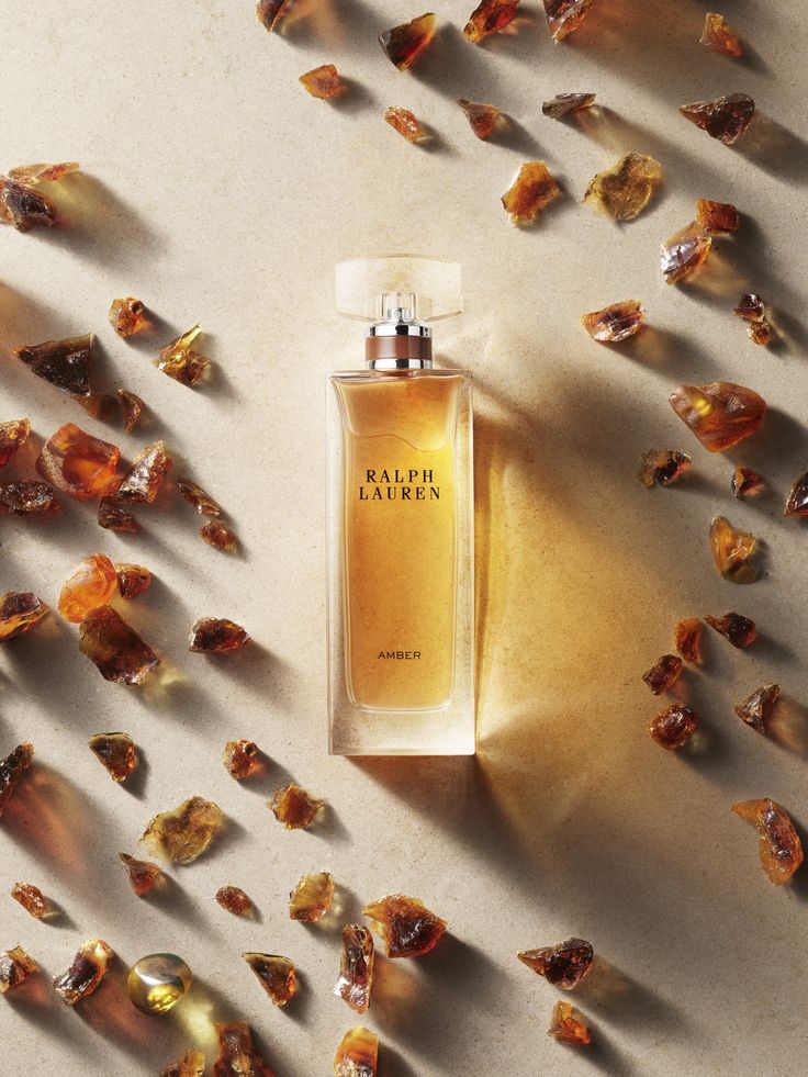 a bottle of perfume sitting on top of a table next to dried up flowers and leaves