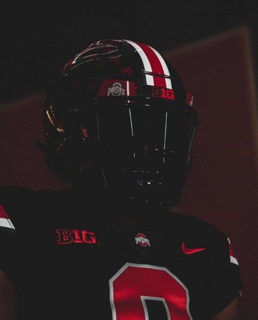 a football player wearing a black uniform with red and white stripes on it's chest