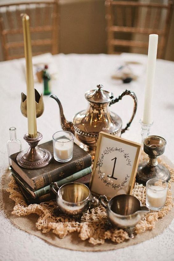 a table topped with books and candles on top of a white cloth covered tablecloth