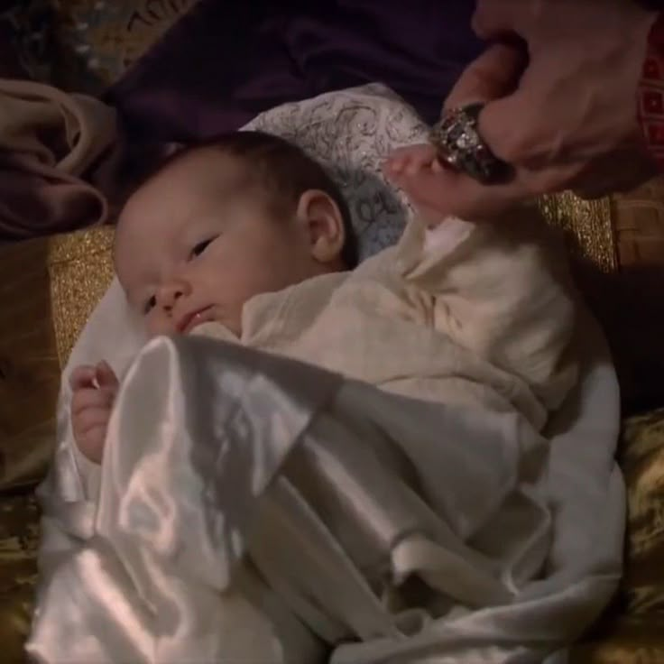 a baby wrapped up in a blanket being held by someone