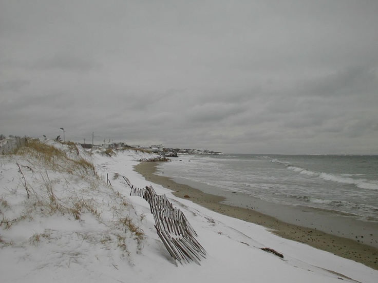 a beach covered in snow next to the ocean