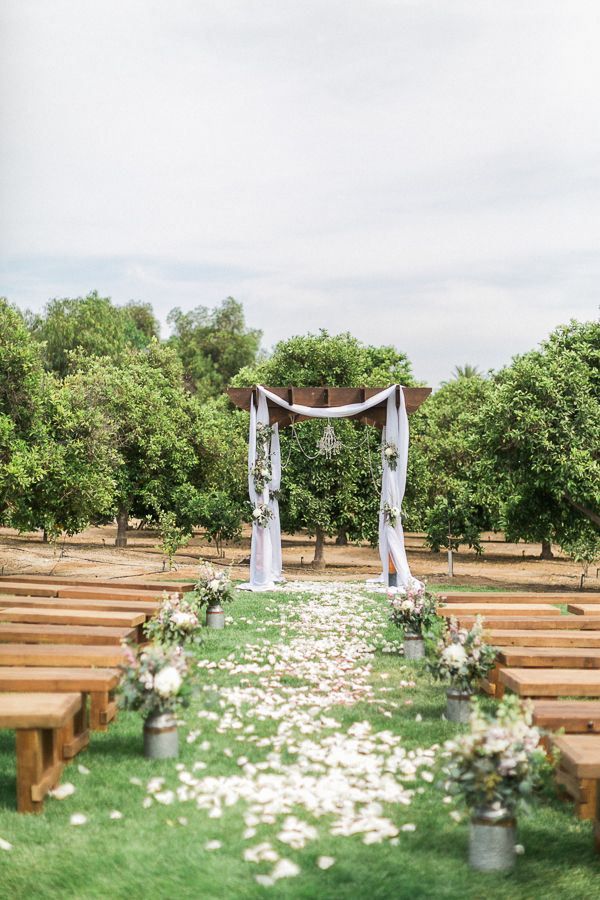 an outdoor ceremony setup with white flowers and greenery