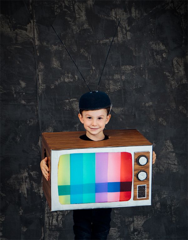 a young boy is holding up a television costume that has been made to look like an old tv