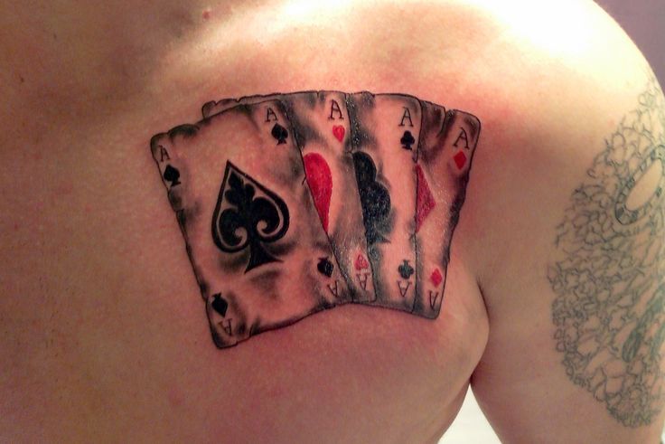 a tattoo on the back of a man's shoulder with playing cards and spades