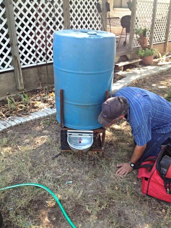 a man is working on a tank in the yard with a hose attached to it